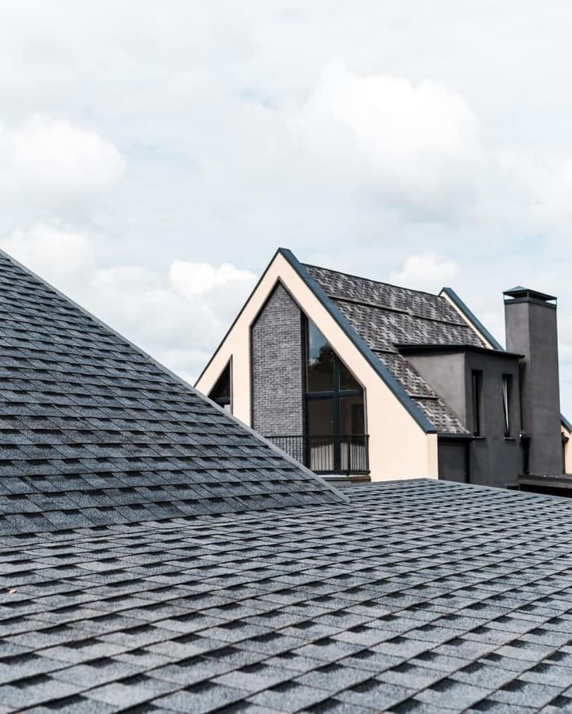 Architectural asphalt shingle roof on a pitched residential roof under an overcast sky