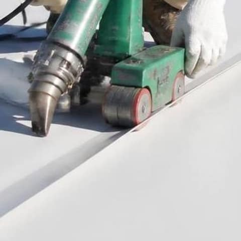 Hot-air seam welder and roller sealing a seam on a roof membrane
